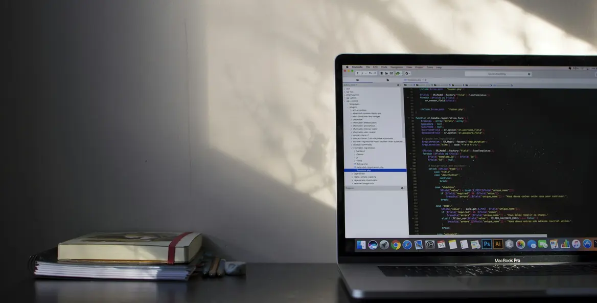 Laptop showing code beside notebooks