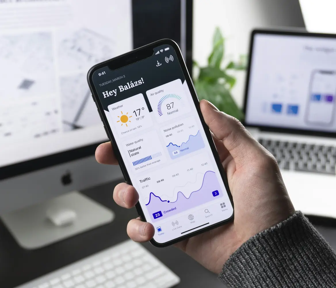 Hand holding a phone showing an app dashboard